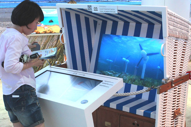 Various touchscreens and other interactive devices are mounted inside actual beach chairs within the Germany Pavilion, allowing visitors to explore a variety of topics relating to coastal areas.